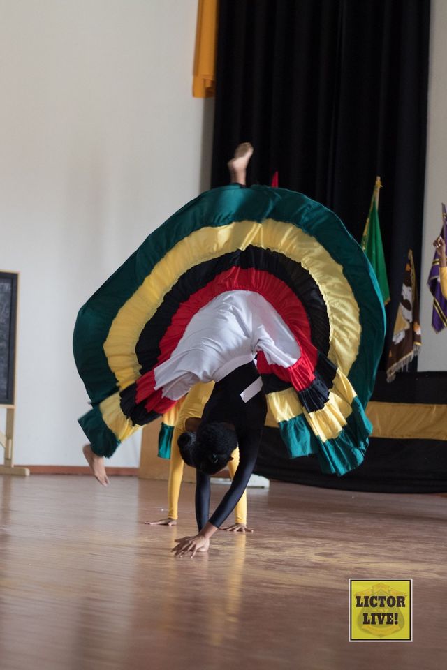 <strong>Cartwheel in Motion</strong><br>A dancer of Pilgrim House caught during a cartwheel – one of the complex dance moves employed as she dances at the Inter-House Dance Competition of 2019. The dance competition is an annual school event that commemorates the Republic Anniversary of Guyana. The winning house of the Dance Competition usual performs the choreography at the next Market Day.<br>Photo: <em>Lictor Live!</em> Cartwheel in Motion